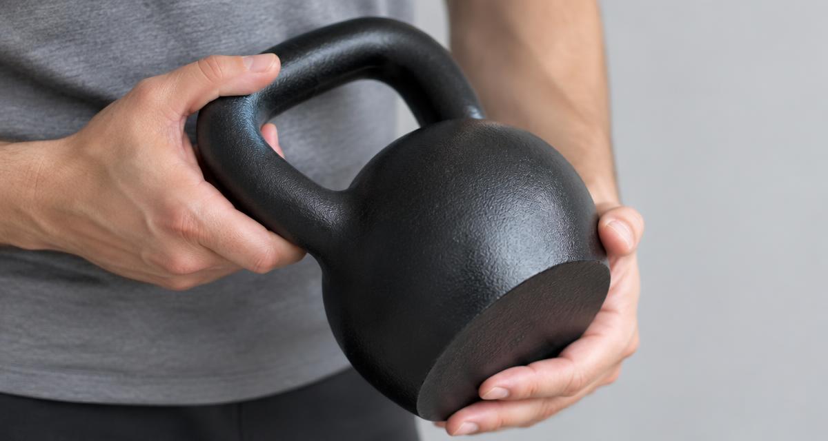 Manos revisando el asa y la base de una kettlebell de hierro fundido